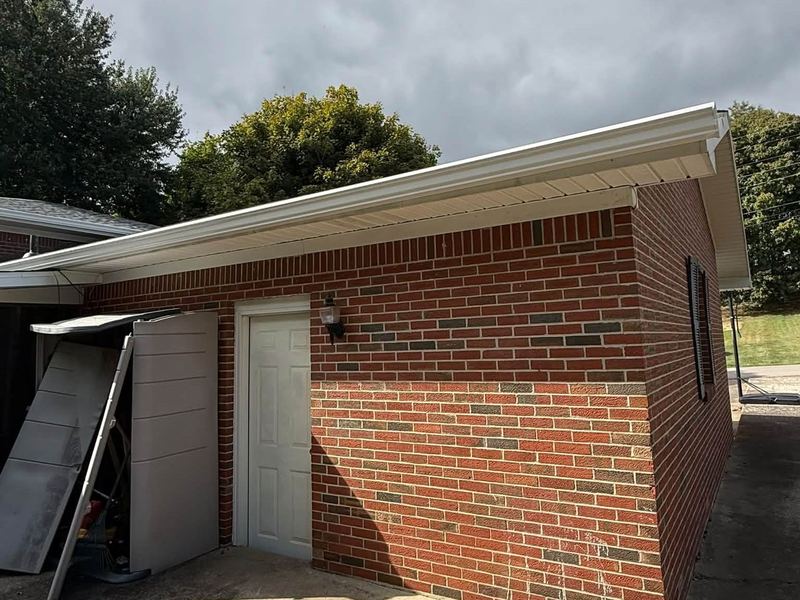 White seamless gutters installed along a brick garage near Louisville, KY